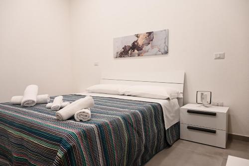 a white bedroom with a bed with towels on it at Dimora Domitia - Apartments in Mondragone