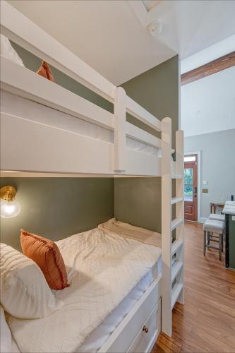 a bedroom with a bunk bed with white bunk beds at Elledot Cottage in Summerville