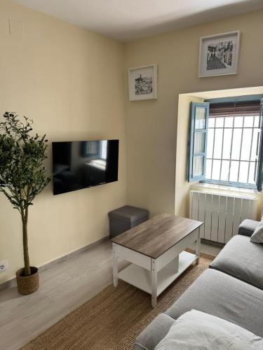 un soggiorno con tavolo e TV a parete di Casa Castillo Vejer a Vejer de la Frontera