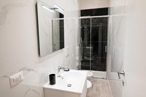 a white bathroom with a sink and a mirror at Dimora Domitia - Apartments in Mondragone