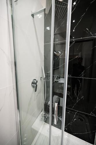 a glass shower in a bathroom with a man in the mirror at Dimora Domitia - Apartments in Mondragone