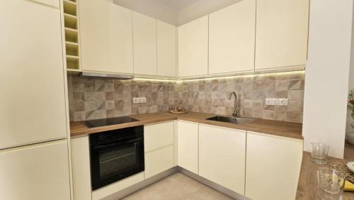 a white kitchen with white cabinets and a sink at Serenata in Corfu Town