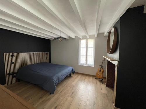 a bedroom with a bed and a guitar in it at Maison du bonheur in Combres