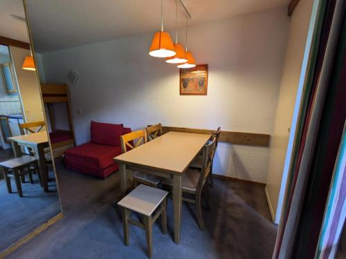 une chambre avec une table, des chaises et un canapé rouge dans l'établissement Résidence Les Chalets des Arolles - maeva Home - Studio 4 Personnes - Confort MAE-0014, à La Plagne Tarentaise