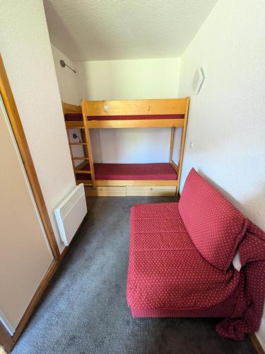 Cette chambre comprend un canapé rouge et des lits superposés. dans l'établissement Résidence Les Chalets des Arolles - maeva Home - Studio 4 Personnes - Confort MAE-0014, à La Plagne Tarentaise
