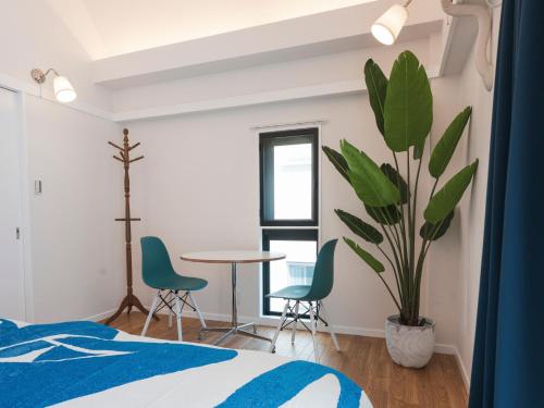a bedroom with a table and chairs and a plant at Ludens House横浜山下公園 in Yokohama