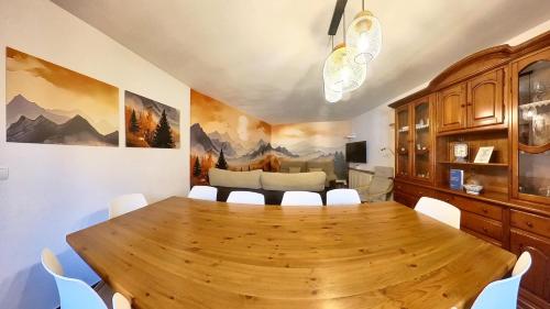 a dining room with a wooden table and white chairs at Casa Pelaire Panticosa -tucasaenlospirineos in Panticosa