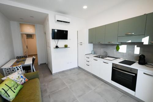 a kitchen with white cabinets and a living room at Dimora Domitia - Apartments in Mondragone