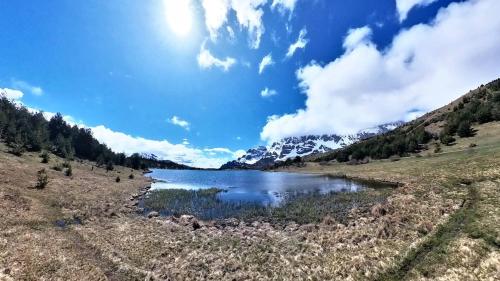 a lake in the middle of a field with mountains at Casa Pelaire Panticosa -tucasaenlospirineos in Panticosa