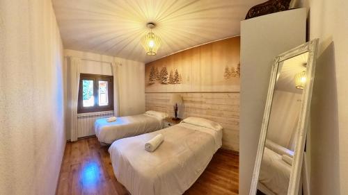 a room with two beds and a mirror at Casa Pelaire Panticosa -tucasaenlospirineos in Panticosa