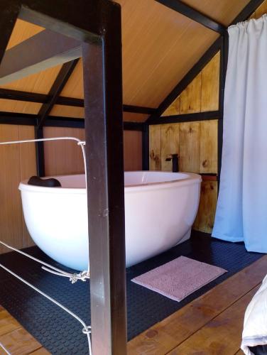 eine Badewanne in einem Raum mit Holzdecke in der Unterkunft Ecovalle São Thomé - Cabana Mallki Wasi in São Thomé das Letras