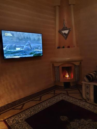 マラケシュにあるCharmant Riad avec piscine, au Coeur de Marrakechのリビングルーム(暖炉、薄型テレビ付)