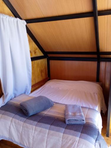 ein Bett in einem Holzzimmer mit einer weißen Tagesdecke in der Unterkunft Ecovalle São Thomé - Cabana Mallki Wasi in São Thomé das Letras