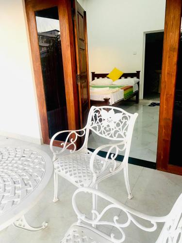 a white chair and a bed in a room at Sahan Tourist House in Polonnaruwa