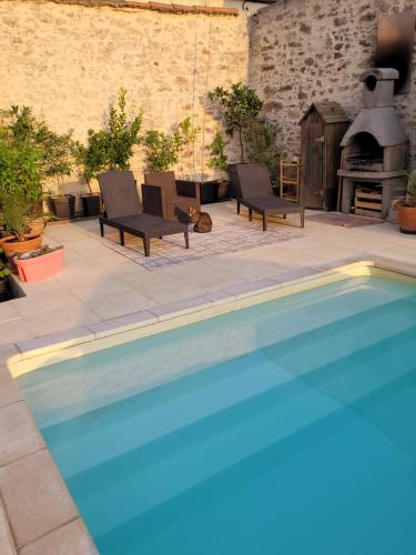 einen Pool mit 2 Stühlen und einem Kamin in der Unterkunft Gîte de la tour avec piscine entre Carcassonne et narbonne in Capendu