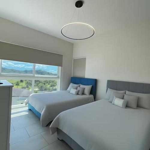 a bedroom with two beds and a large window at AmazINN Places Playa Escondida in María Chiquita