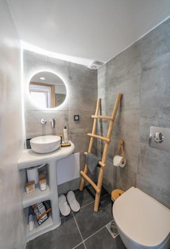 a bathroom with a sink and a toilet and a mirror at Pezoula Traditional House with Sunrise View in Santorini