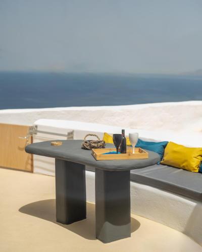 a table in front of a couch with a beach at Pezoula Traditional House with Sunrise View in Santorini