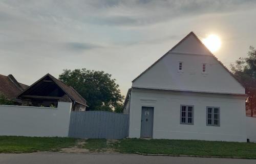 a white house with a fence in front of it at Éden Garten Vendégház in Magyarpolány