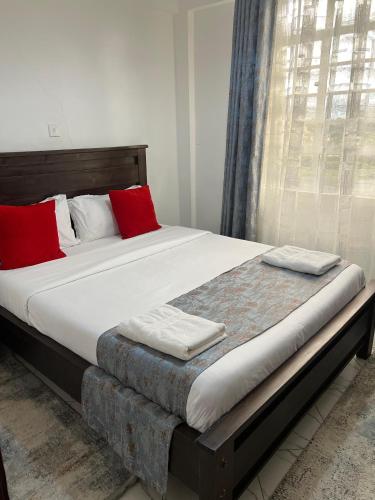 a bed with two red pillows on top of it at The pine 1 bedroom house California plaza in Nanyuki
