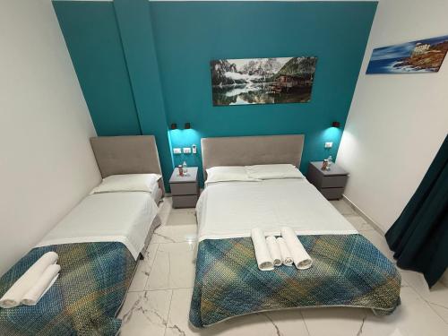two beds in a room with blue walls at Luna Guest House in Pisa