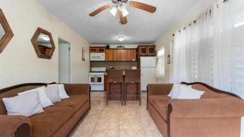 a living room with two brown couches and a kitchen at The Reef 1 walking disntance to Steps Beach in Rincon
