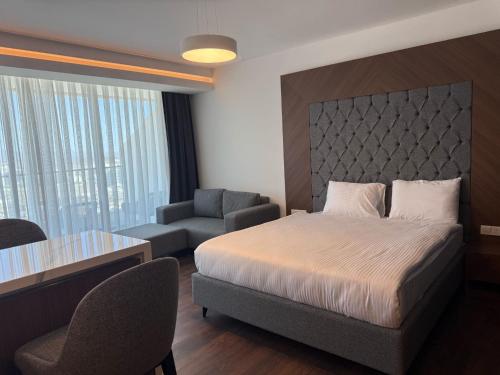 ein Schlafzimmer mit einem Bett, einem Stuhl und einem Tisch in der Unterkunft Grand Sapphire Luxury Residence in Iskele