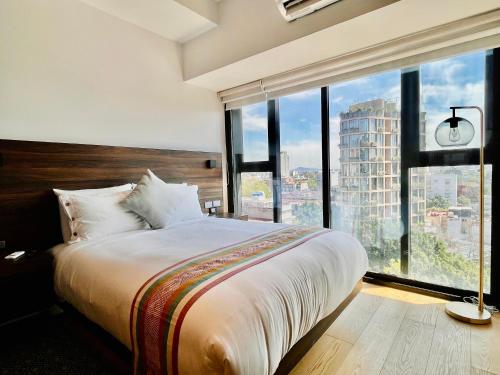 a bedroom with a large bed and large windows at I811 LOFT AC premium amenities in Mexico City
