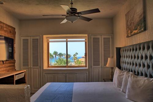 a bedroom with a bed with a ceiling fan and a window at Princesa -C206- Arcade Game -Experience Rocky Point- in Puerto Peñasco