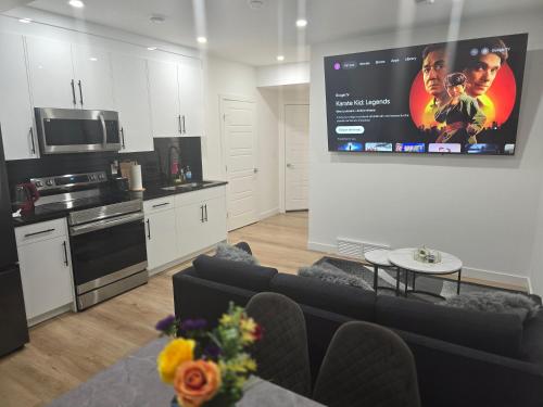 a kitchen and a living room with a large screen at Cozy 2-Bedroom Basement Suite Just Minutes from the Airport in Calgary