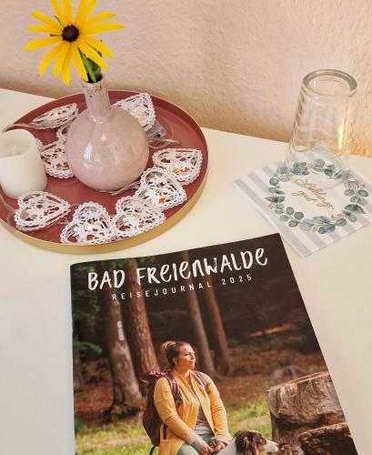 a magazine sitting on a table next to a table with a vase at Pension im Gesundbrunnental in Bad Freienwalde