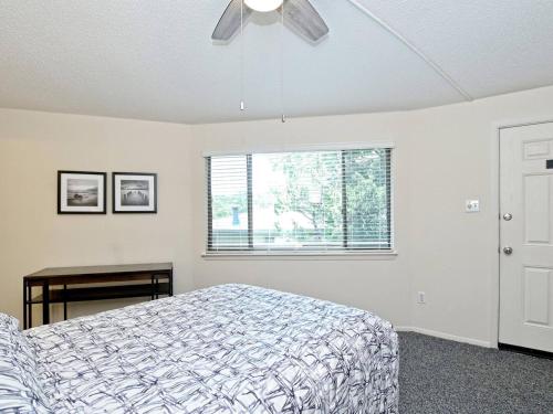 a bedroom with a bed with a ceiling fan and a window at Lakefront Bungalow With Community Poolhot Tub #4 in Lakeway