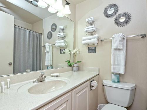 a bathroom with a sink and a toilet and a mirror at Lakefront Bungalow - Community Poolhot Tub #10 in Lakeway