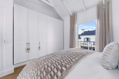a white bedroom with a bed and a large window at Modern Coastal Townhouse at The Majestic in Kalk Bay