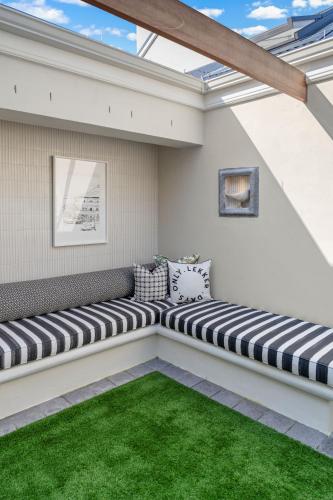 a patio with a bench with a green lawn at Modern Coastal Townhouse at The Majestic in Kalk Bay