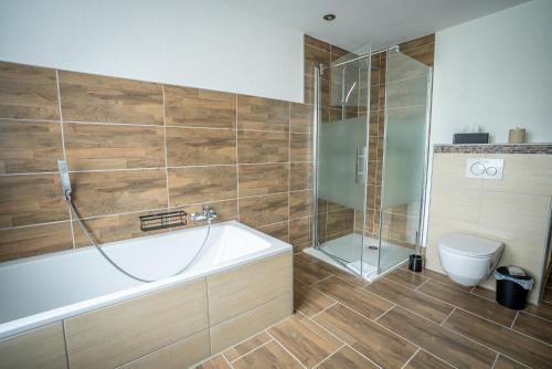 a bathroom with a tub and a shower and a toilet at BacherlHouse - Apartment Ager in Schörfling