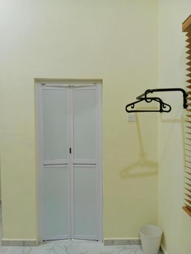 a white closet in a white wall with a hanger at Homestay Mini in Bukit Payong