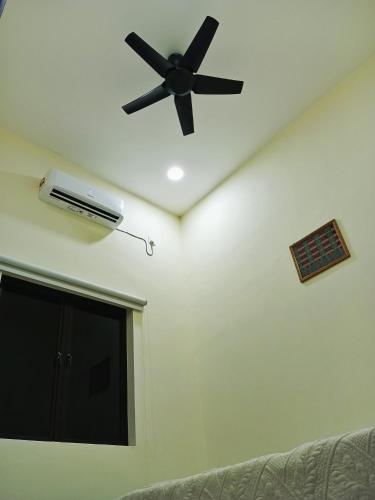 a ceiling fan in a living room with a couch at Homestay Mini in Bukit Payong