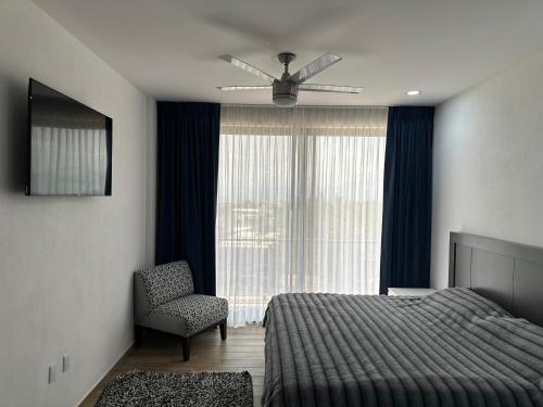 a bedroom with a bed and a chair and a window at Luxor and Condo Hotel in Ajijic