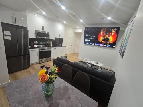a living room with a table and a tv on the wall at Cozy 2-Bedroom Basement Suite Just Minutes from the Airport in Calgary