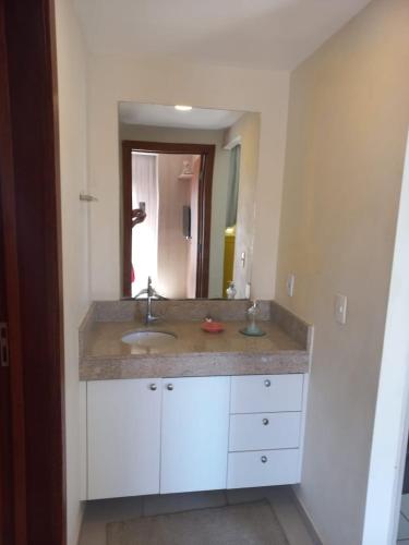 a bathroom with a sink and a large mirror at Flat Luxuoso e Romântico no Quartier com Vista in Barra do Piraí