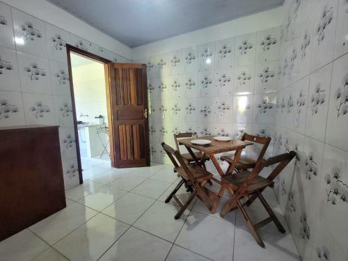a dining room with a wooden table and chairs at Quarto Compartilhado na Praça de Serra Grande in Uruçuca