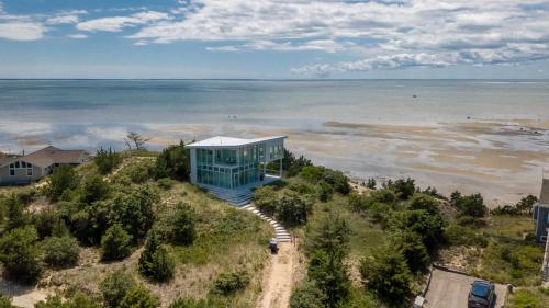 a blue house on top of a hill next to the ocean at Waterfront Hot Tub Sauna Private Beach in Wellfleet