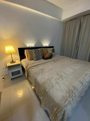 ein Schlafzimmer mit einem großen Bett und einer Lampe auf einem Tisch in der Unterkunft Bekipay Suite at One Palm Tree right across NAIA 3 in Manila