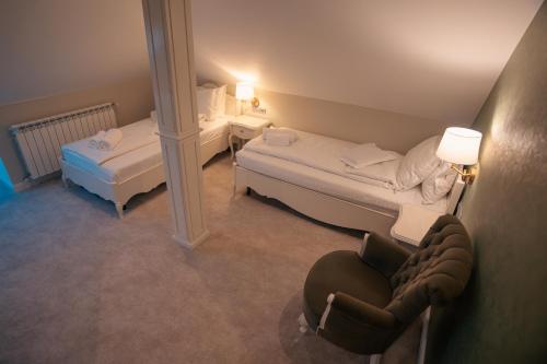 a small room with two beds and a chair at Strindberg Boutique Hotel in Topliţa