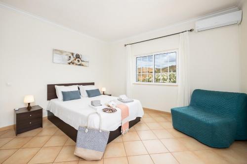 a bedroom with a bed and a blue chair at Villa Entrecolinas in São Bartolomeu de Messines