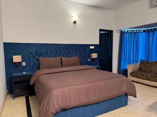 a bedroom with a large bed and a chair at Arizona Lodge 2 in Islamabad