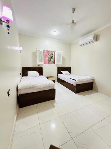 two beds in a room with white tile floors at Habob Nubian Guest House in Aswan