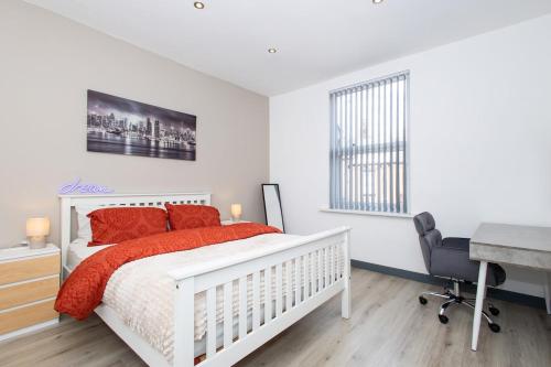 a bedroom with a white bed with red pillows and a desk at Home Near Leeds City Centre & Elland Road in Beeston