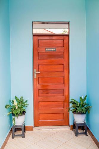 a wooden door with two potted plants in front of it at Avek Home Stay Ngorongoro Room in Uru